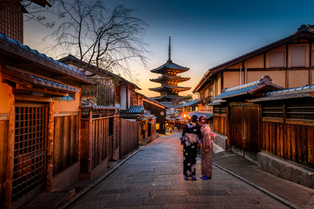 A traditional street and illuminated pagoda in Kyoto at dusk